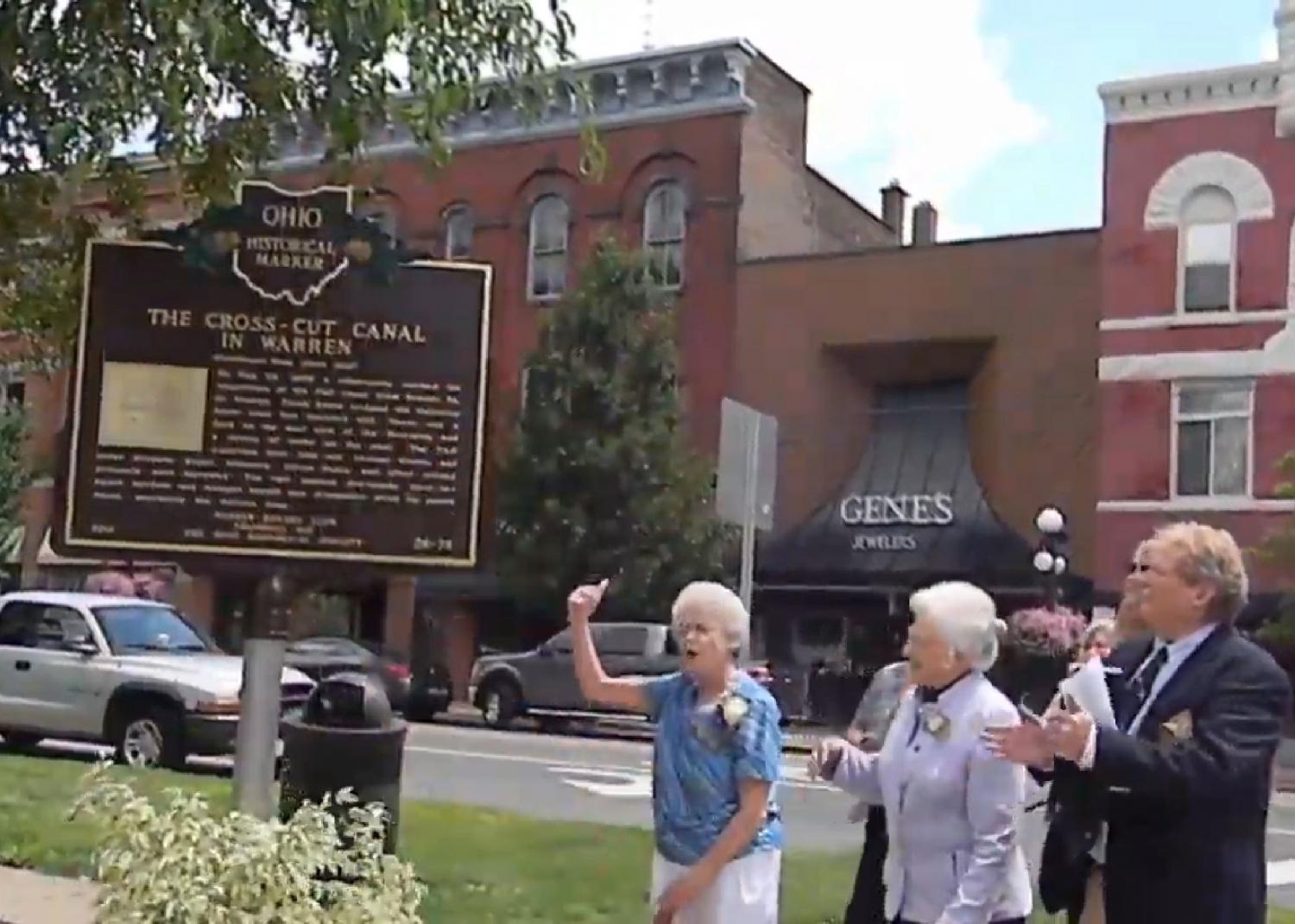 Janice Bland and community members next to commemorative sign.