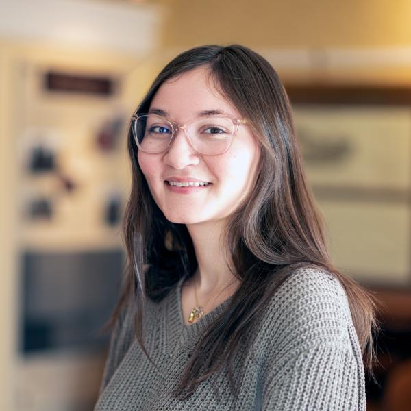 Kendra Harrelson has dark hair and is wearing glasses and a grey sweater.