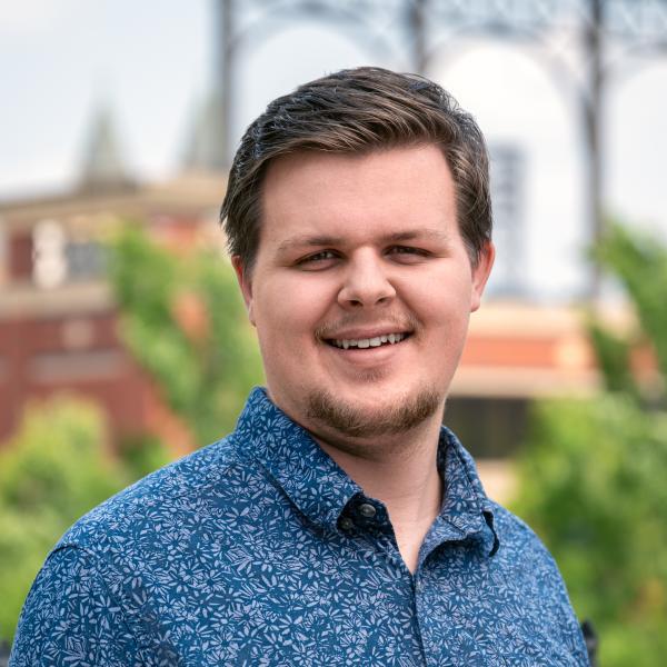 Tanner Crawford in a blue button-up with 717 Credit Union Stadium in the background