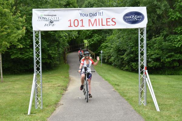 Lisa Curll cycling under the Century Ride finish line.