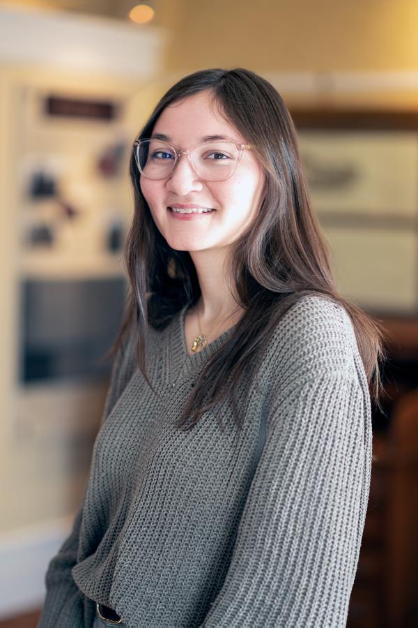 Kendra Harrelson has dark hair and is wearing glasses and a grey sweater.