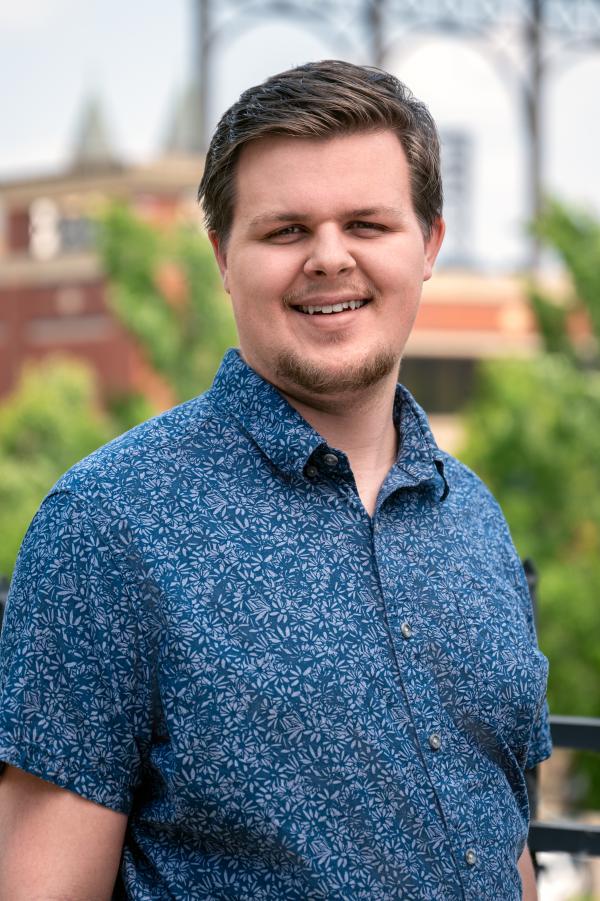 Tanner Crawford in a blue button-up with 717 Credit Union Stadium in the background